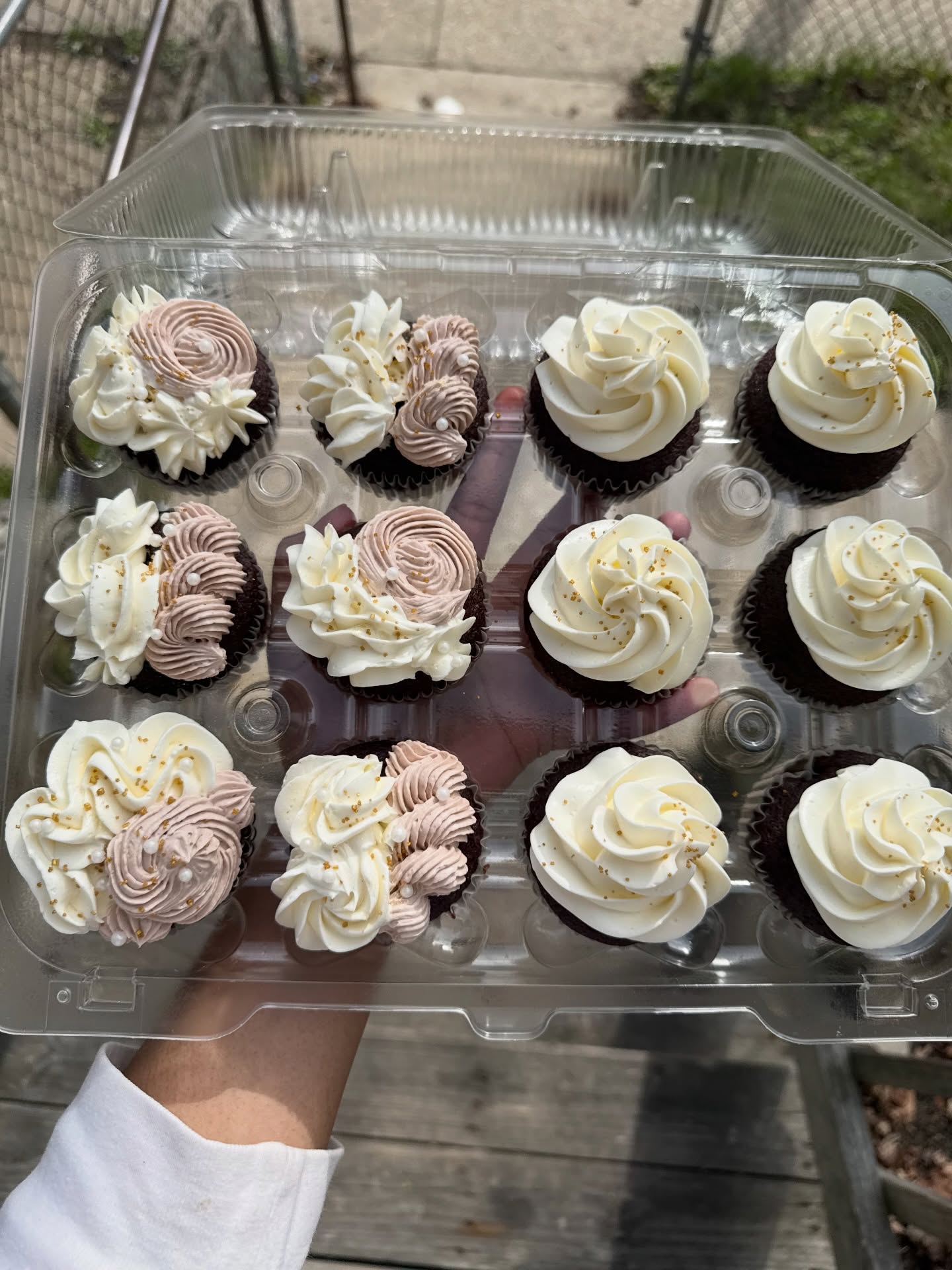 Cupcakes with white and mauve swirled frosting and gold sprinkles in a tray