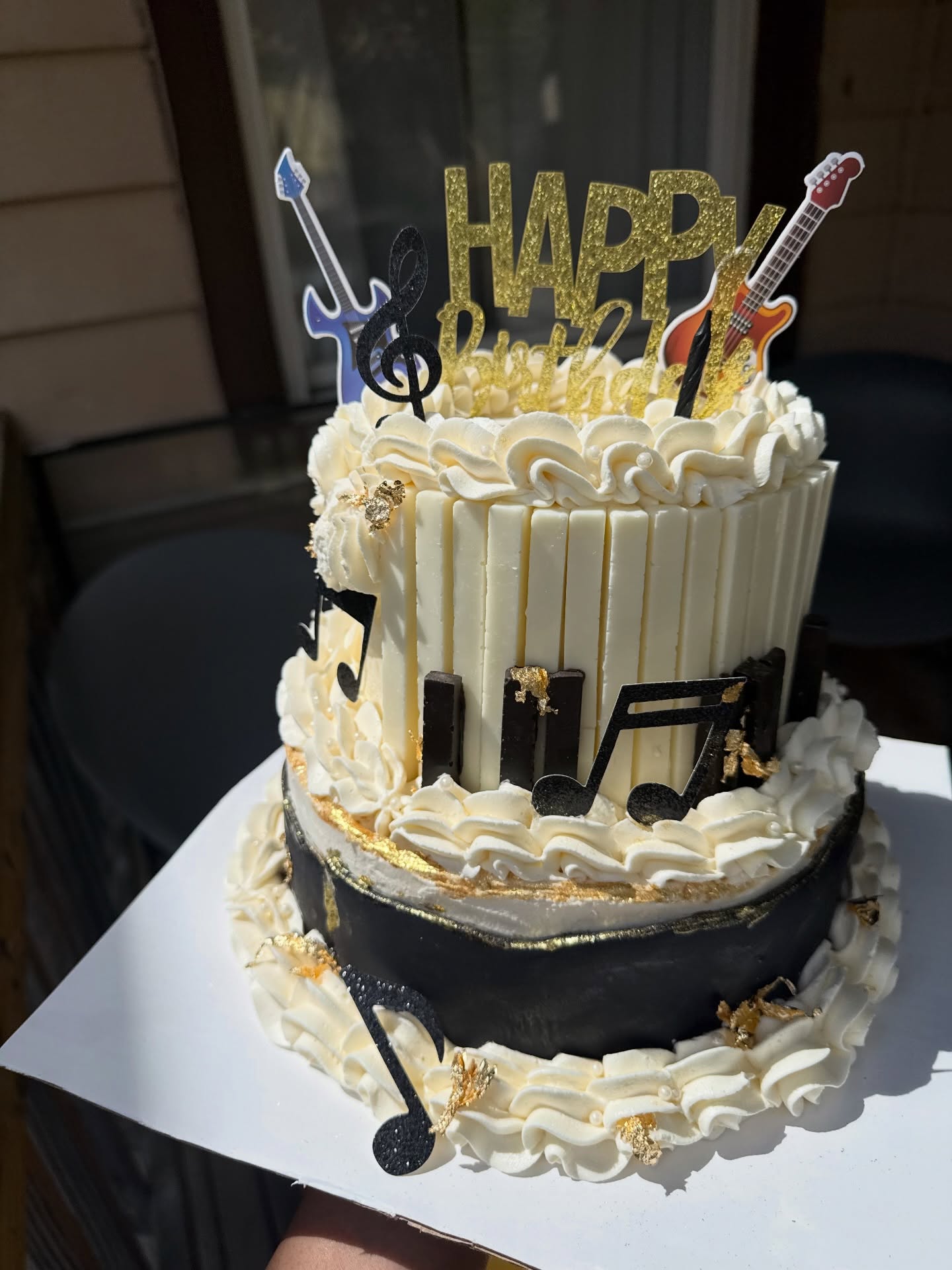 Mini two-tier music-themed cake with a gold Happy Birthday topper, piano keys and guitar picks